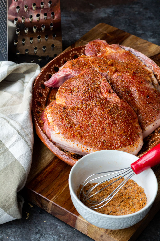 seasoned pork chops with a spice rub on a brown block