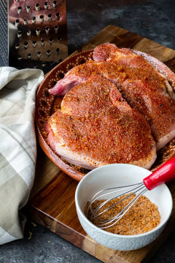 seasoned pork chops with a spice rub on a brown block