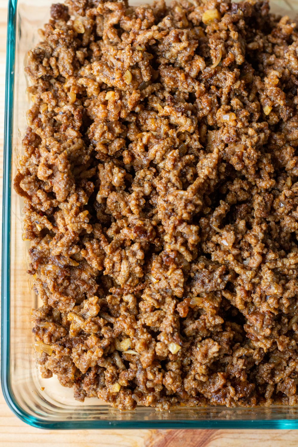 A glass dish full of ground beef enchilada filling.