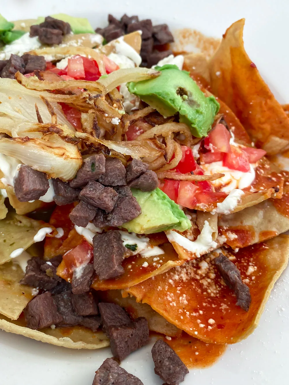 Red and green chilaquiles, smothered corn chips topped with sizzling steak, creamy sauce, and homemade red and green sauces.