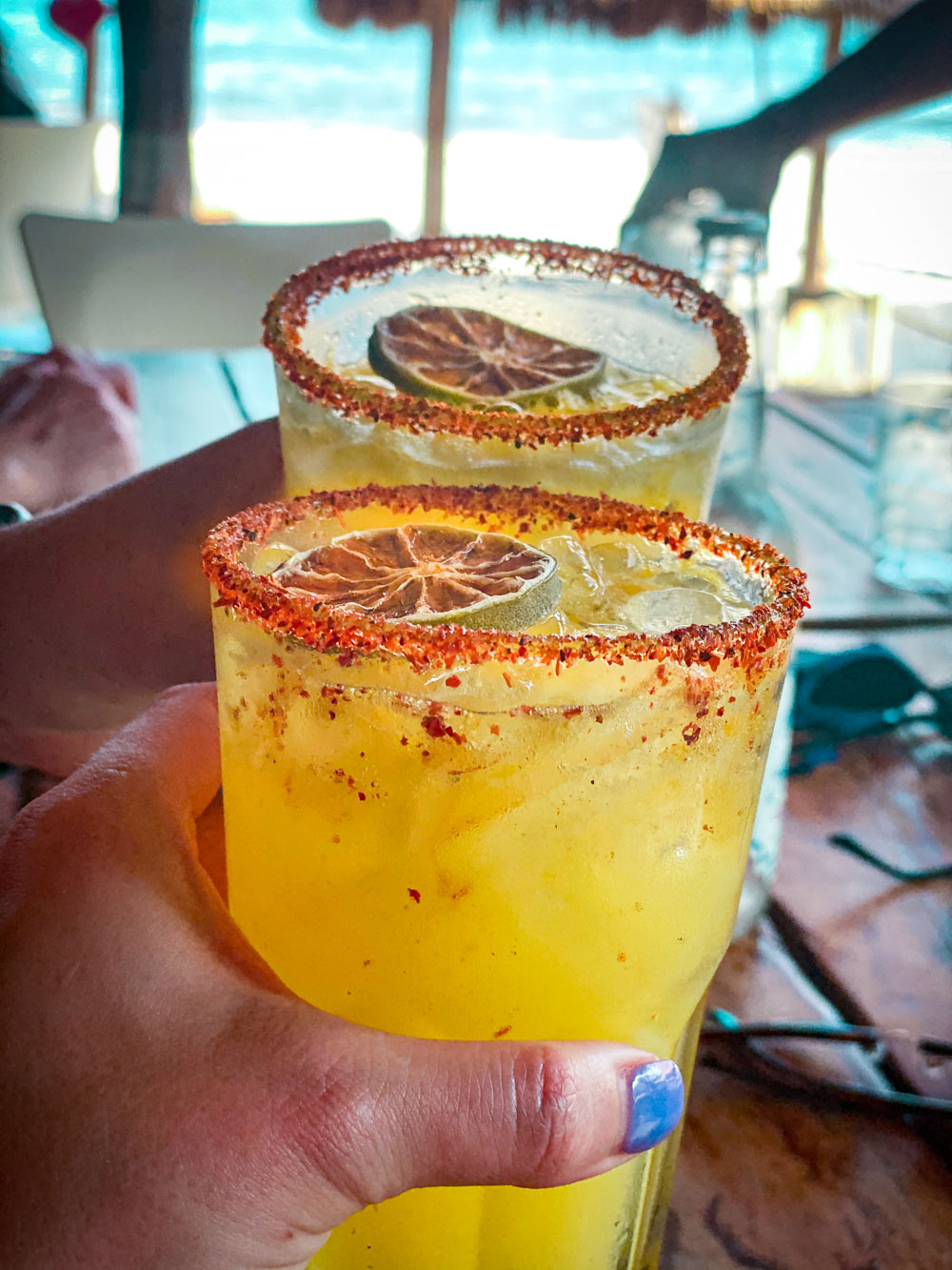 2 hands cheersing passionfruit margaritas at Lido Beach Club in the Yucatan.