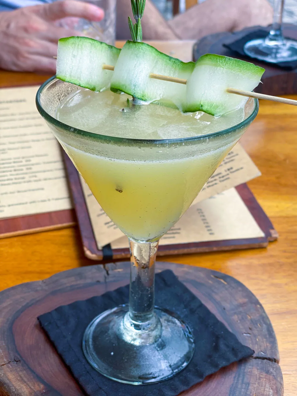 A green cocktail topped with a cucumber ribbon at a restaurant in Playa del Carmen.