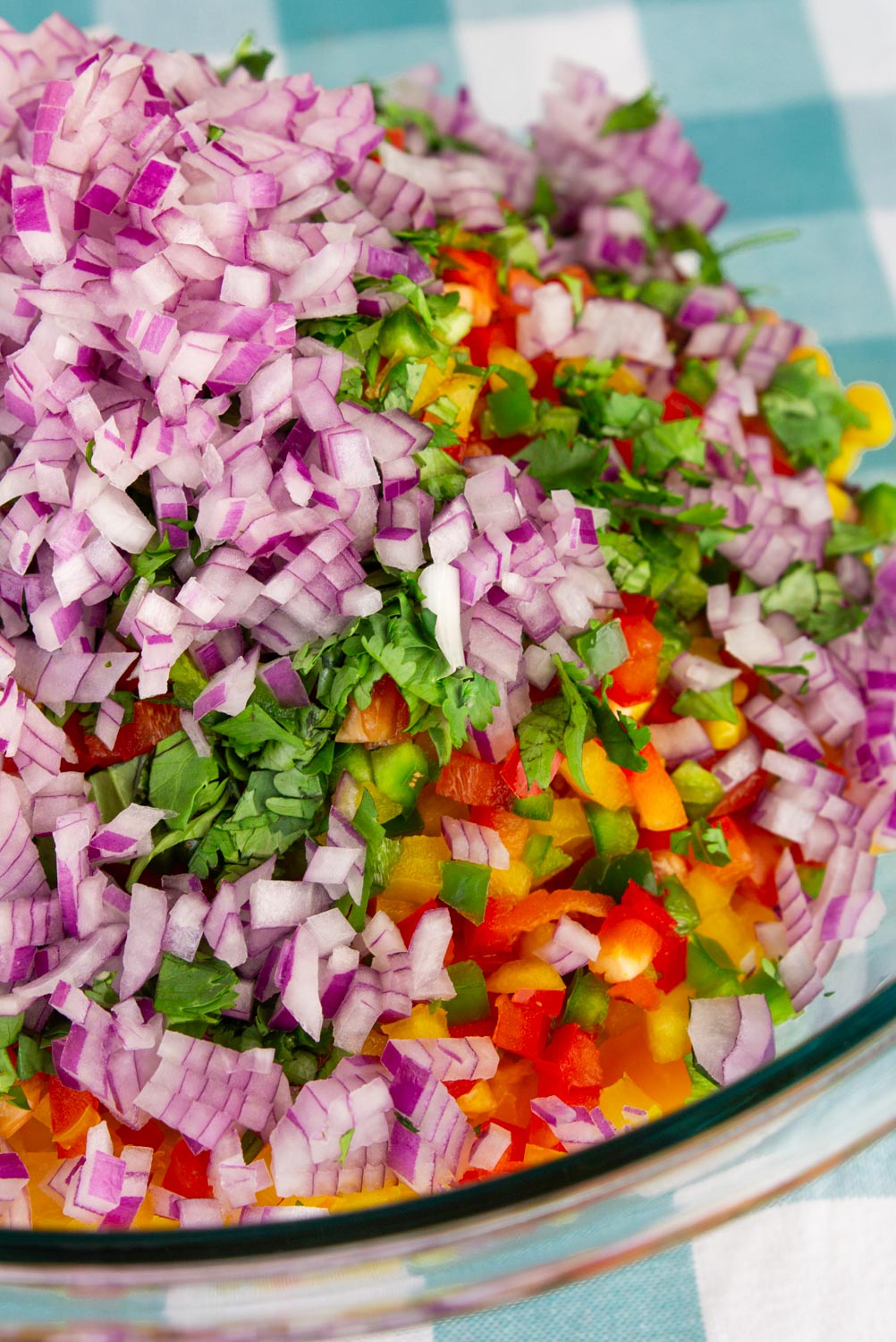 A glass bowl full of vegetables, chopped fine.