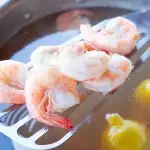 beautiful poached shrimp draining above their broth