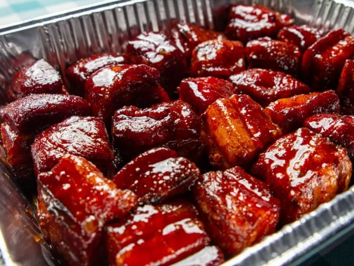 Glazed pork belly in a foil pan with bbq sauce.