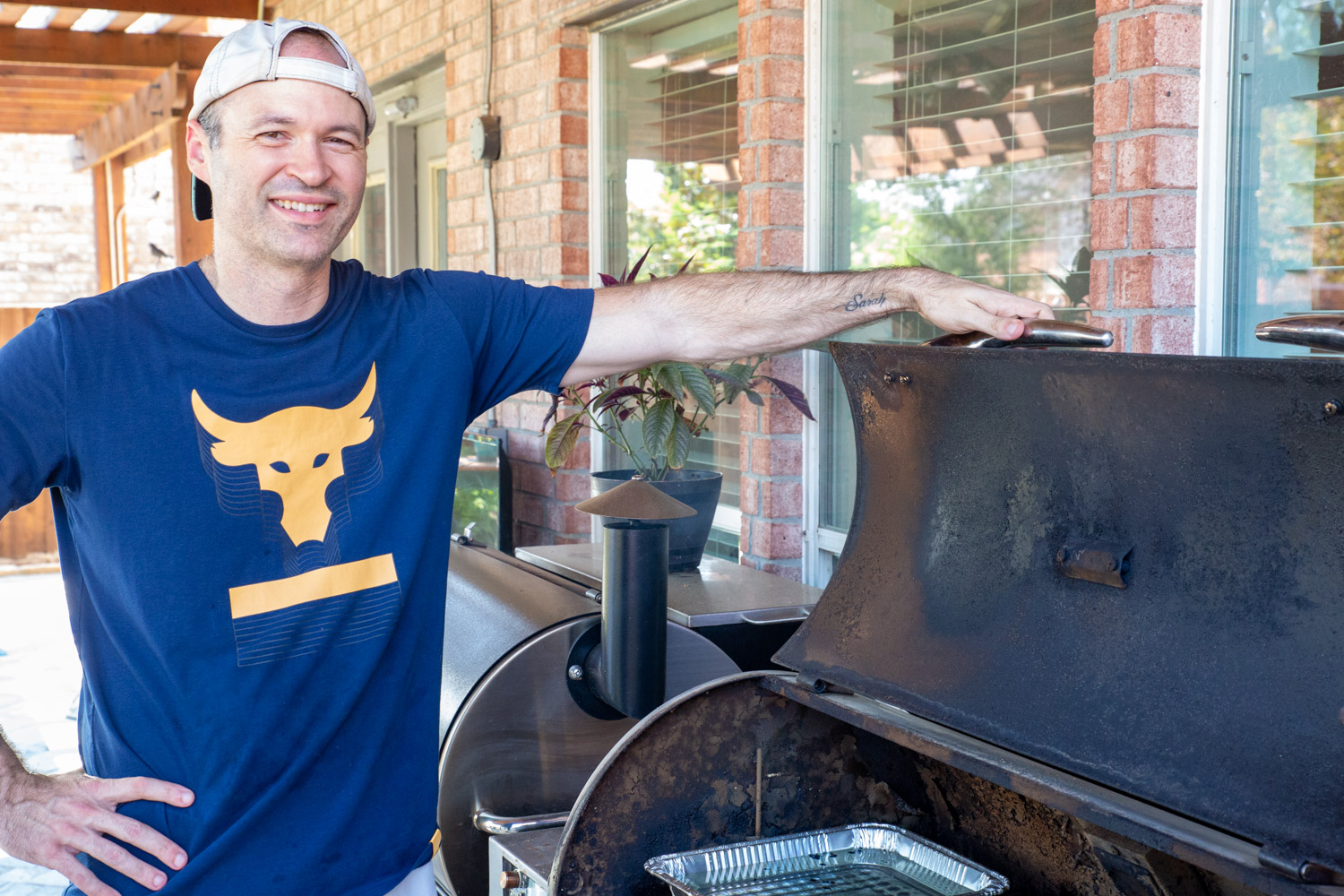 Prepping our barbecue smoker, my husband Dereck poses with the smoker ready to cook.