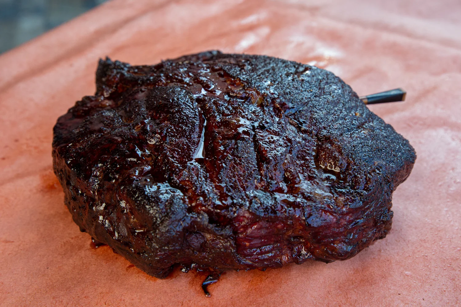Juicy, glistening smoked chuck roast, fresh from the barbecue smoker, on peach paper. 