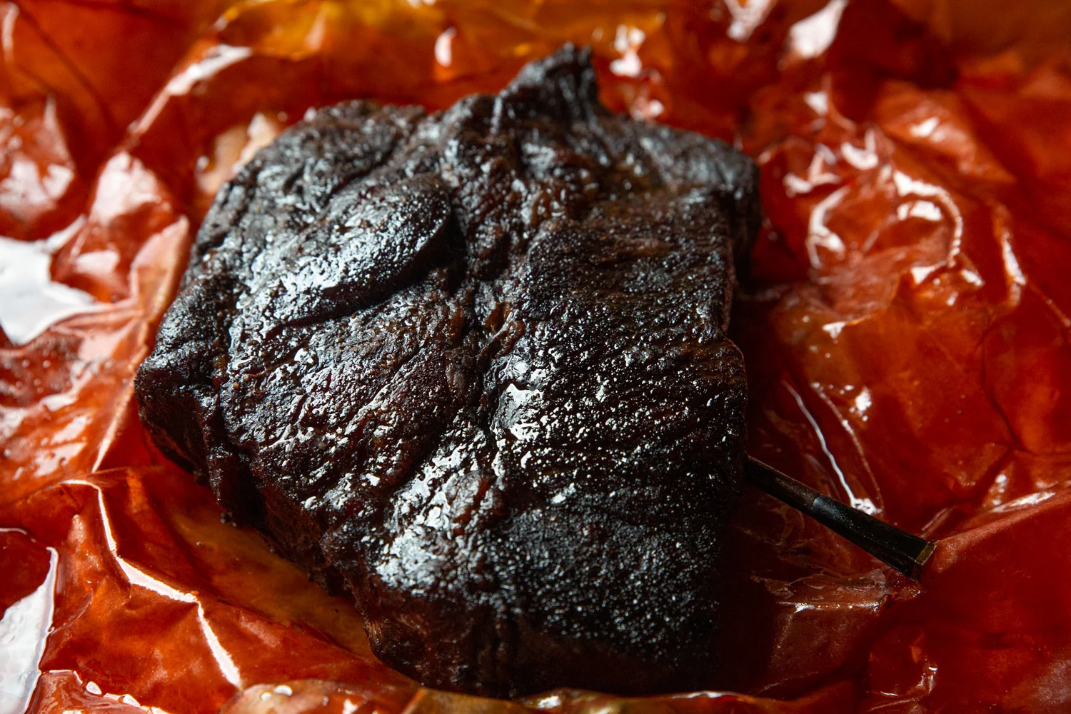 A fully smoked beef chuck roast in peach butcher paper