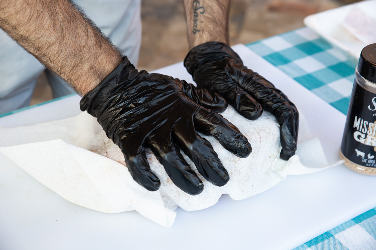 Drying the chuck roast with paper towels wearing gloves.