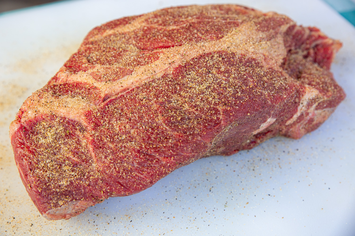 The beef chuck roast, sprinkled liberally (but not fully coated) with beef rub. Red meat is still able to be seen.
