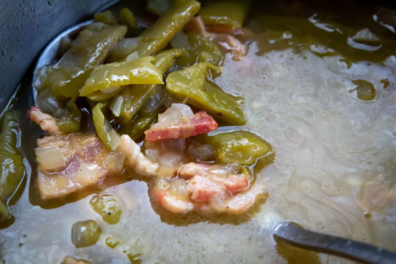 Green beans and bacon simmering in a pot.