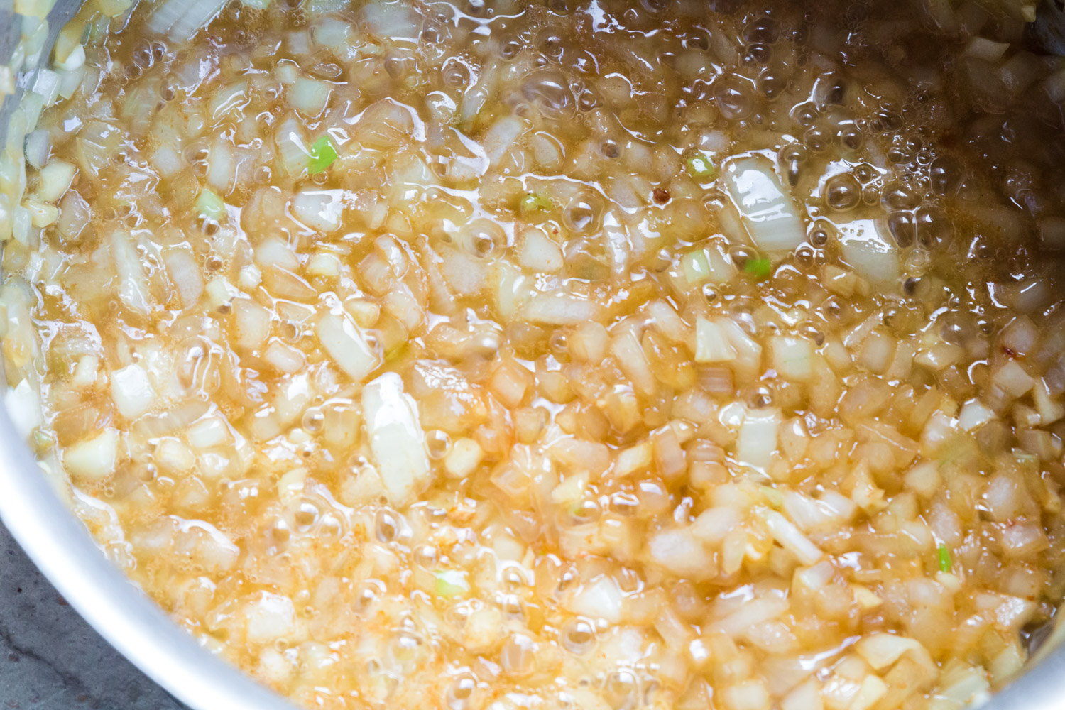 A close up of golden cooked onions and garlic in bacon fat.