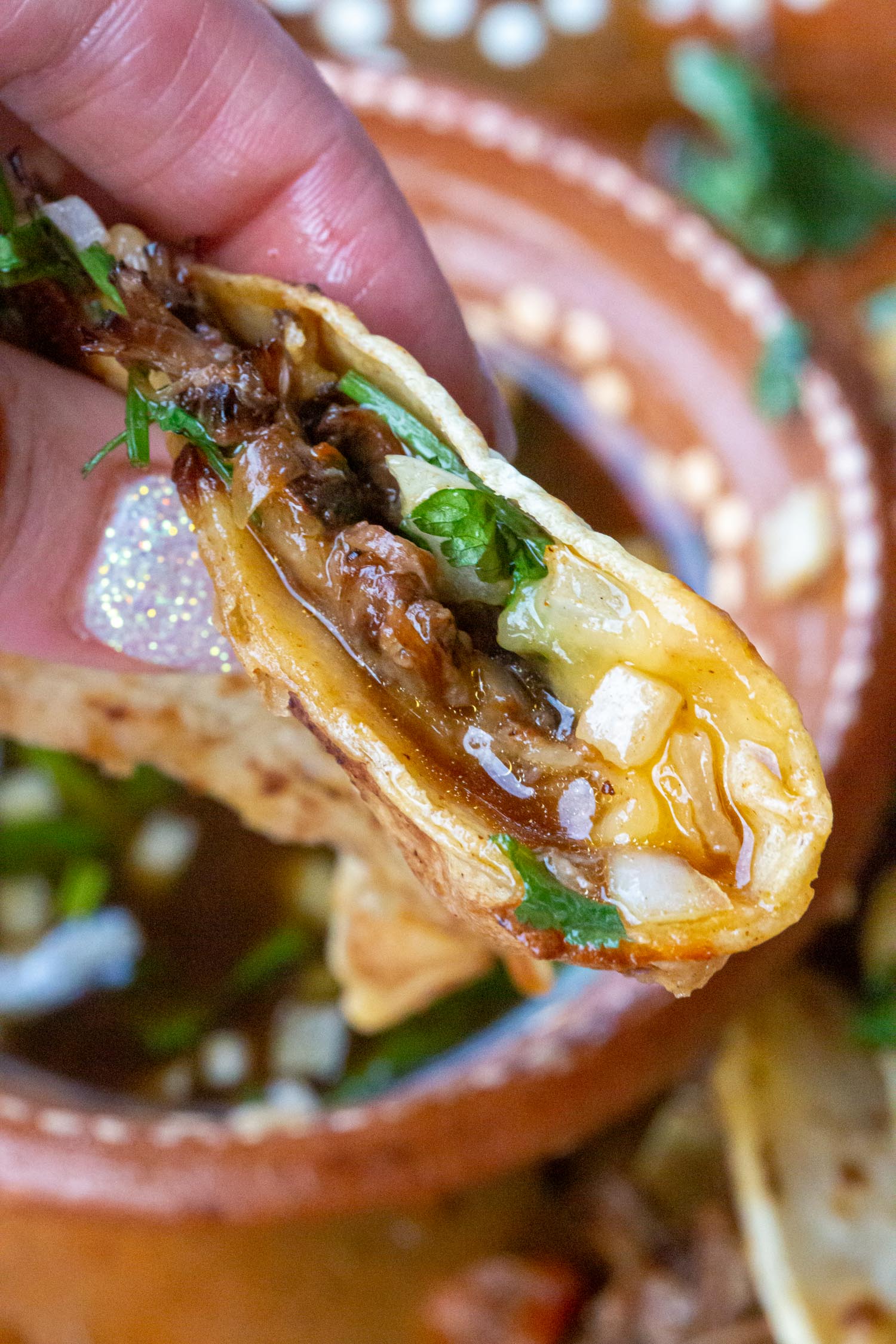 A close up of a birria taco made in the Instantpot with lots of birria sauce.