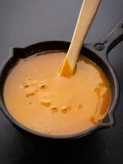 A yellow mustard barbecue sauce in a black skillet with grill brush.