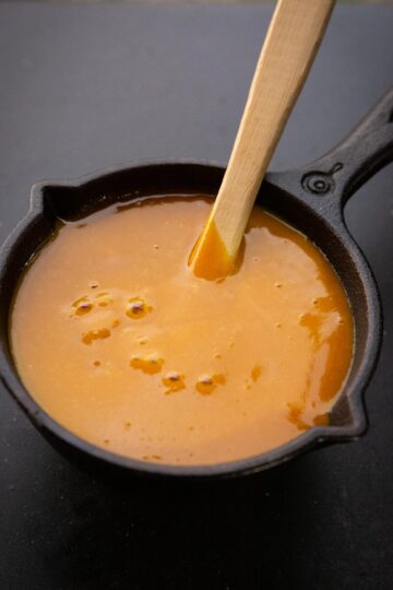 A yellow mustard barbecue sauce in a black skillet with grill brush.