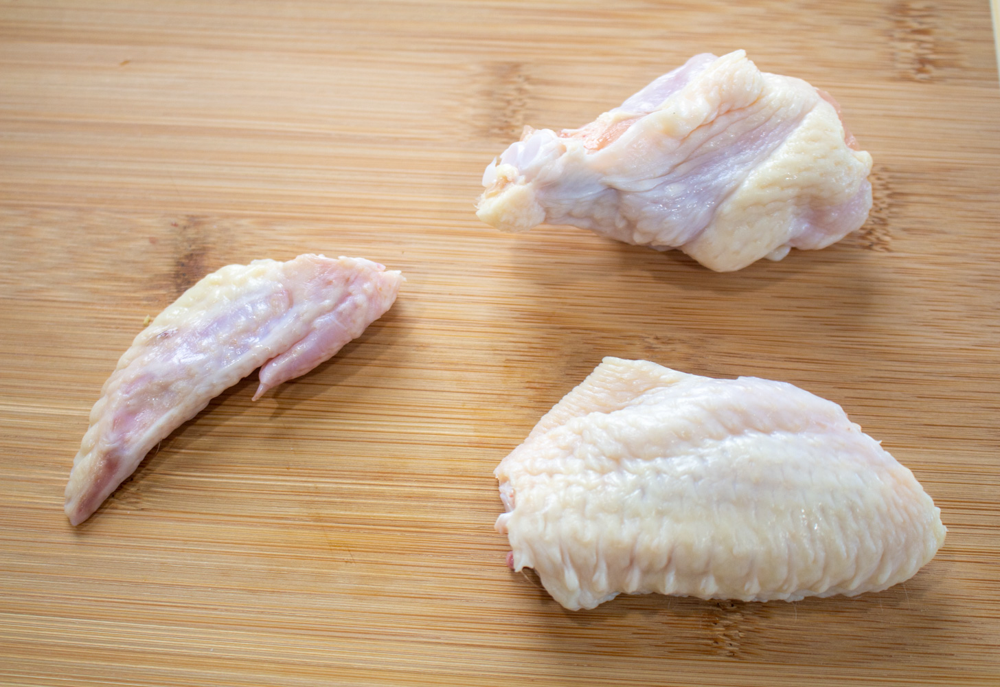 a butchered chicken wing separated into parts: wing, drumette, and wing tip