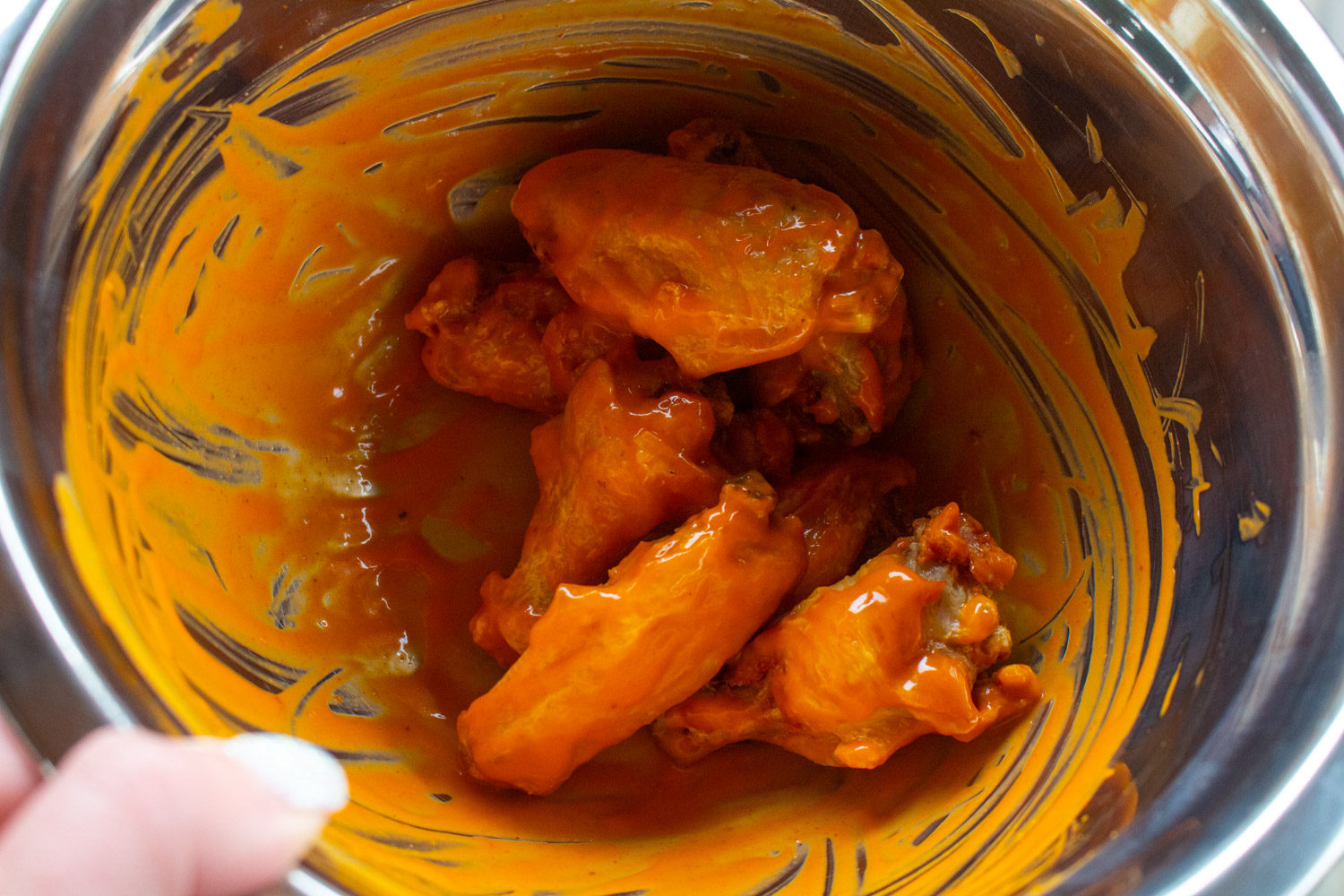 a bowl of buffalo wings in bright red sauce