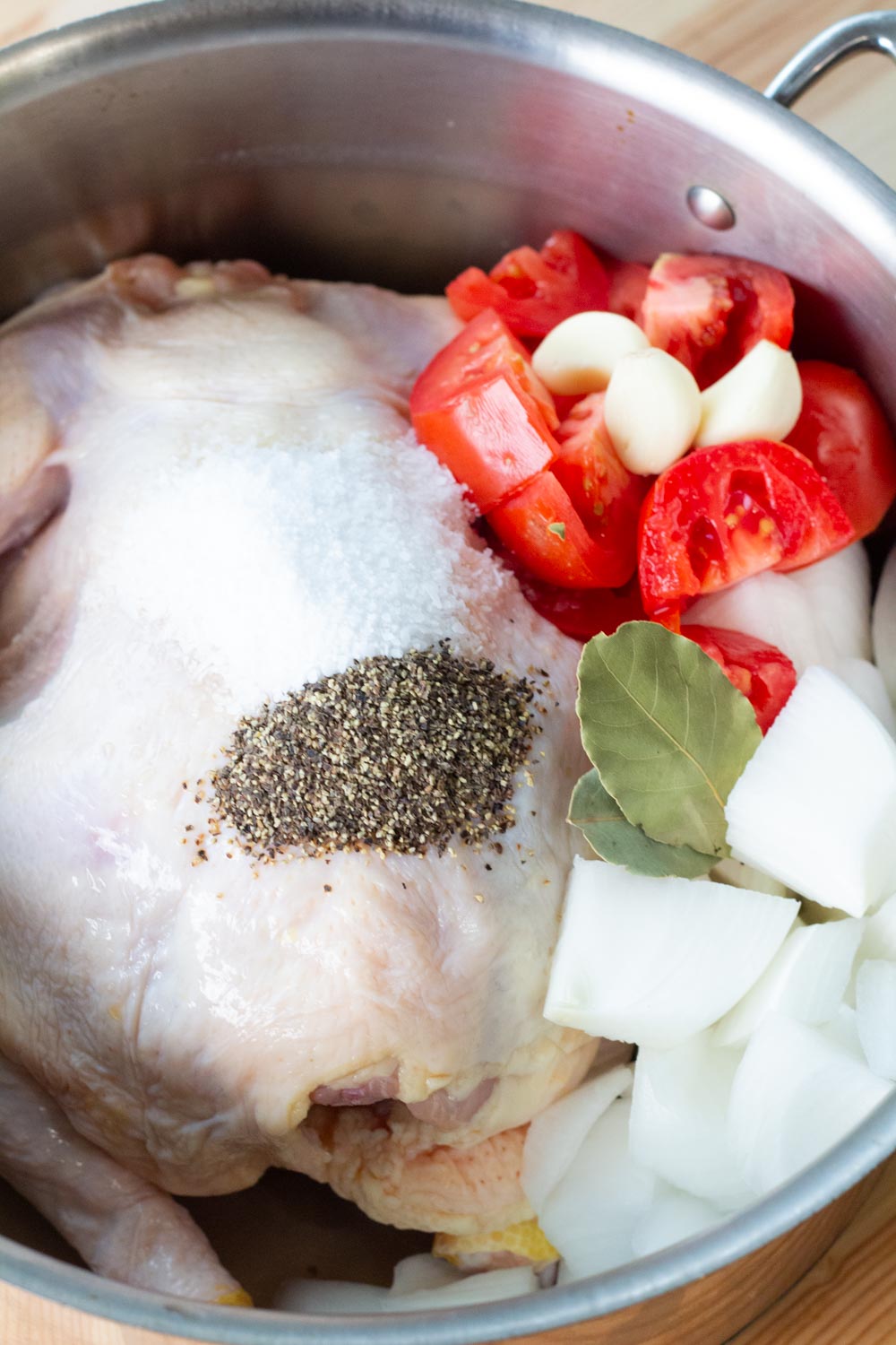 Fresh raw whole chicken in a pot being prepared for boiling. 