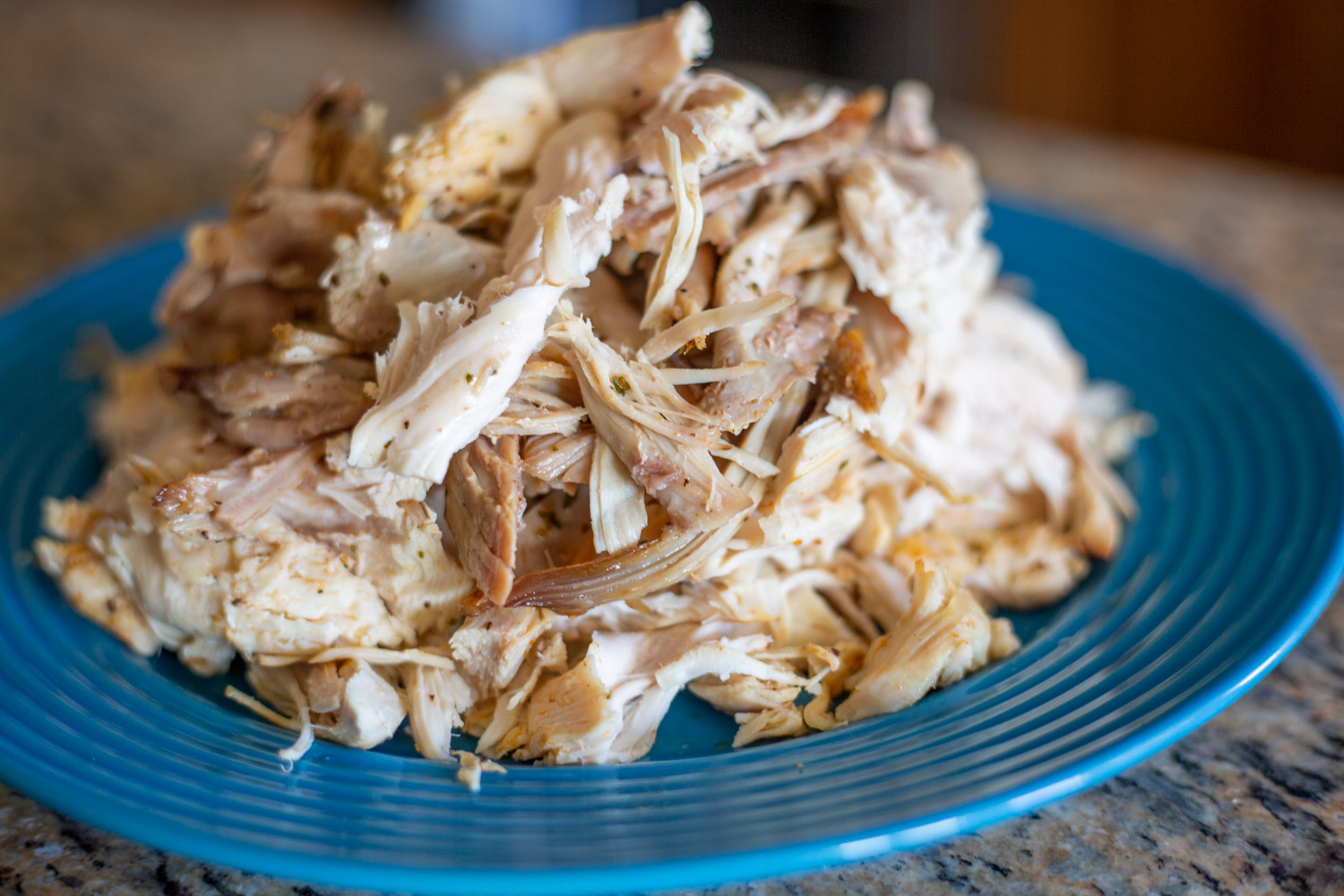 Boiled chicken on a blue plate shredded into bits