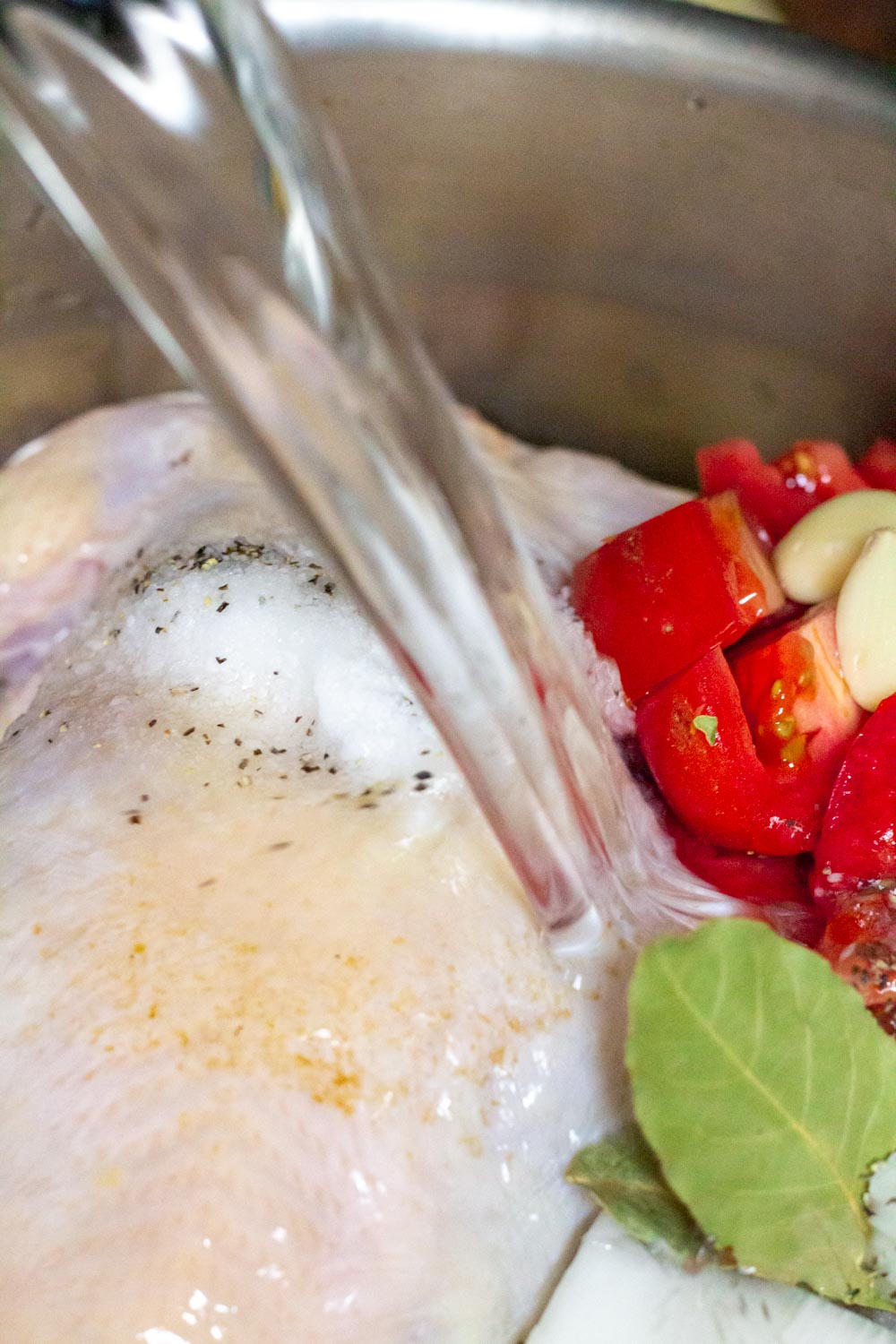 A pot of chicken and vegetables with water being poured in to fill the pot.