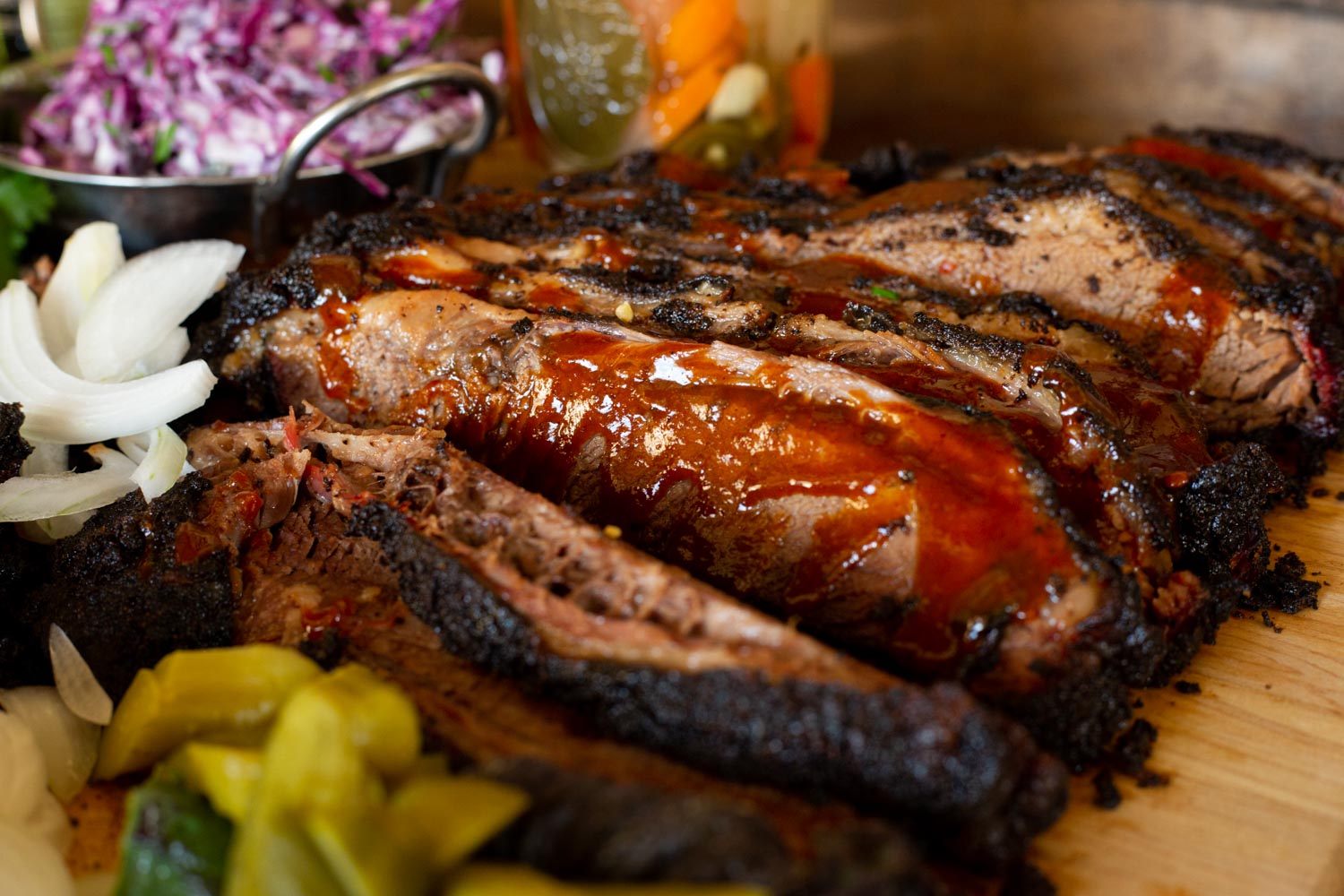 Sliced Black Angus Prime Brisket, displayed on a board drizzled with bbq sauce. 
