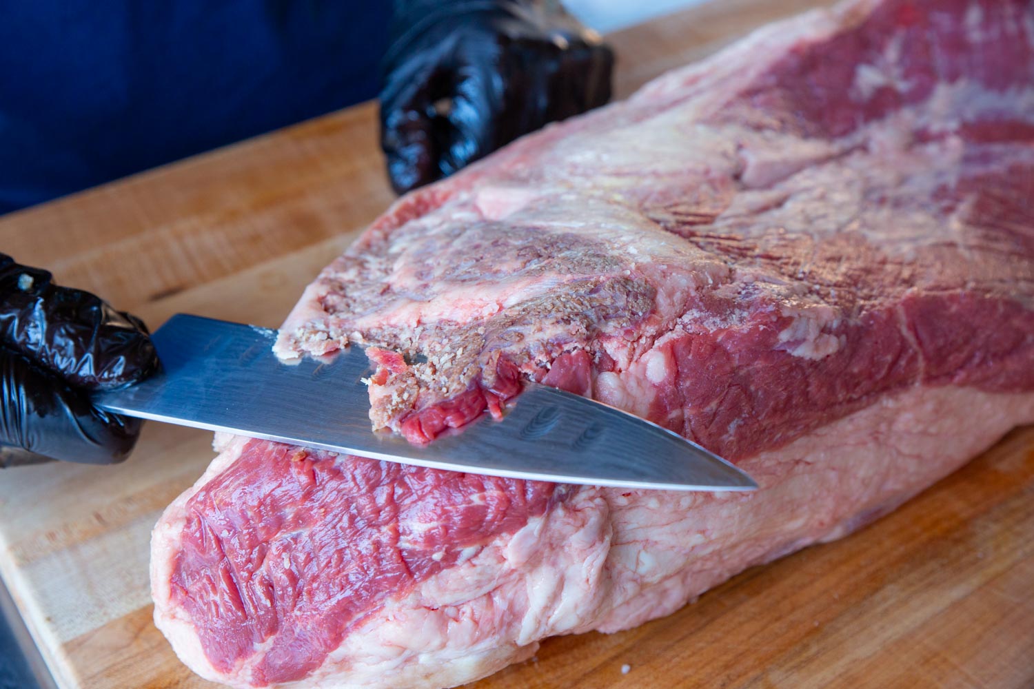 A close up of slicing off any brown spots or silver skin on the brisket. 