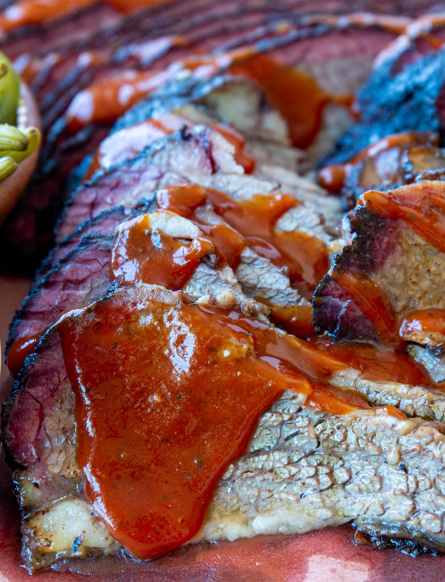 Slices of brisket up-close, dripping with barbecue sauce.