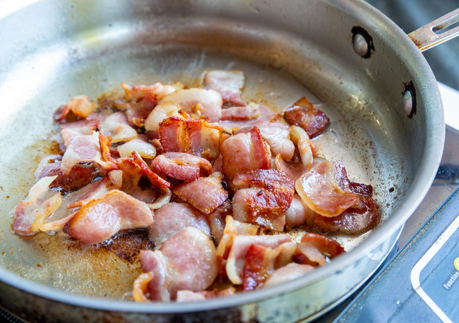 A pan full of pieces of bacon crisping up
