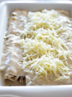 a casserole dish filled with beautiful white sour cream enchiladas topped with cheese