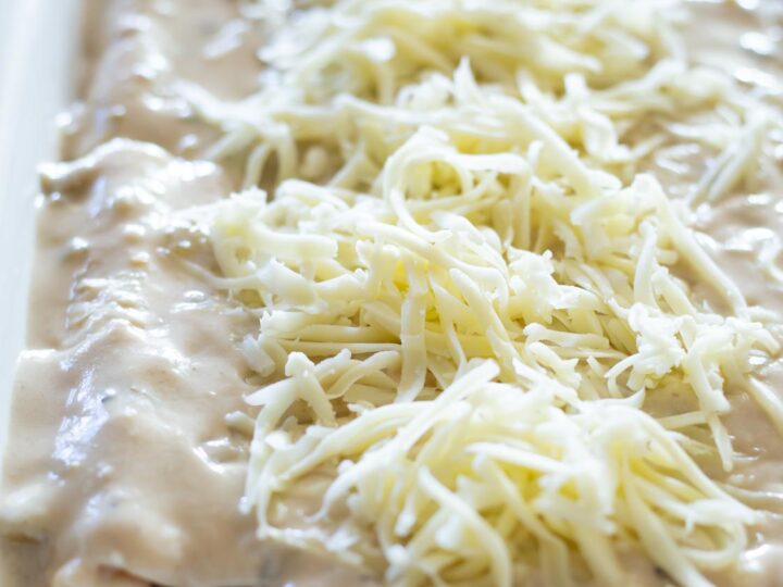 a casserole dish filled with beautiful white sour cream enchiladas topped with cheese