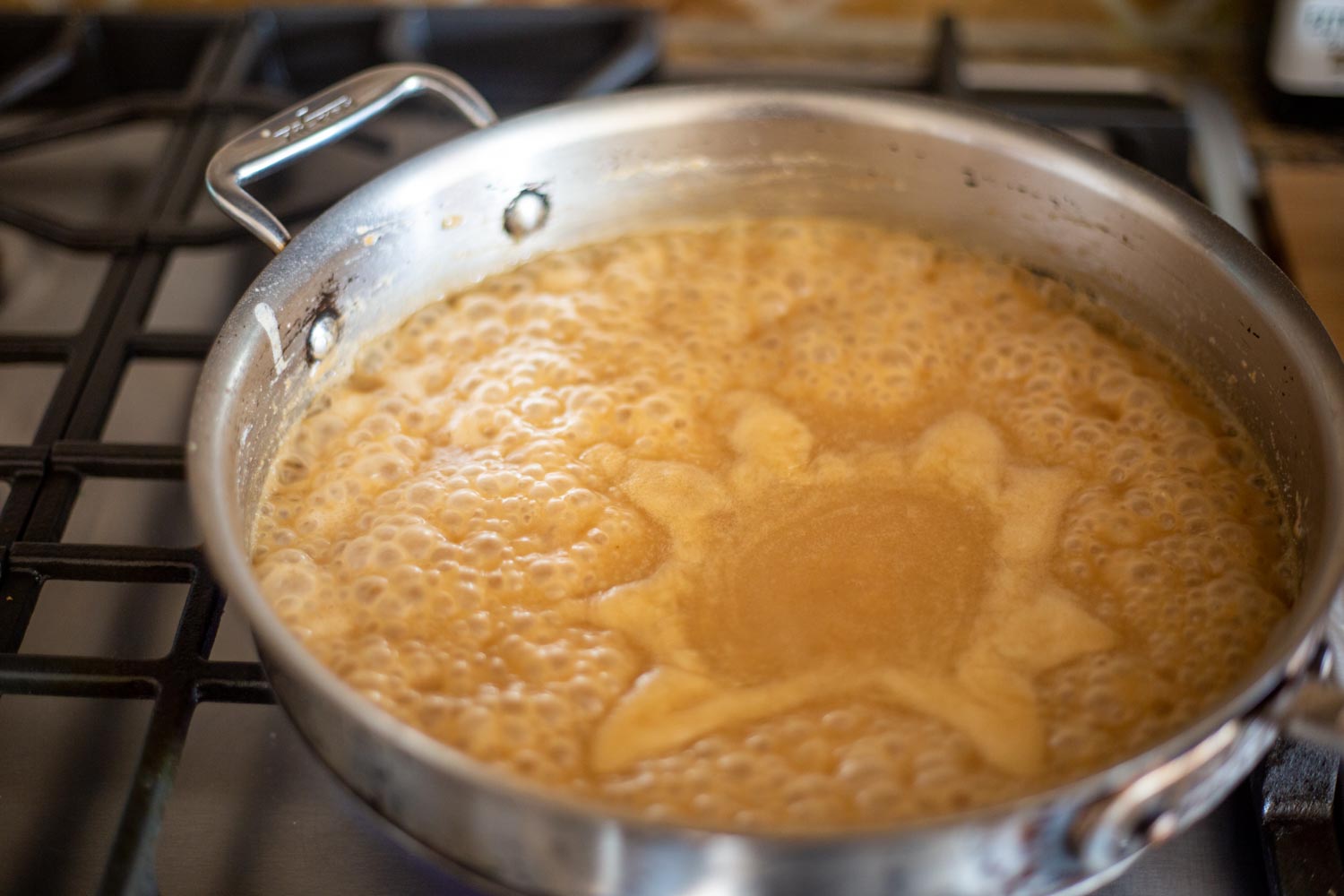 A saucepan full of beef broth thickened with roux and bubbling