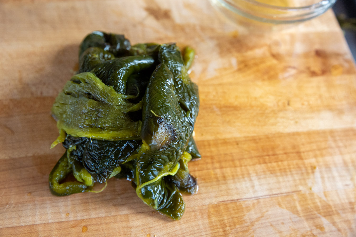 Green chile peppers, roasted, cleaned of skin, and prepped for chopping on a cutting board. 