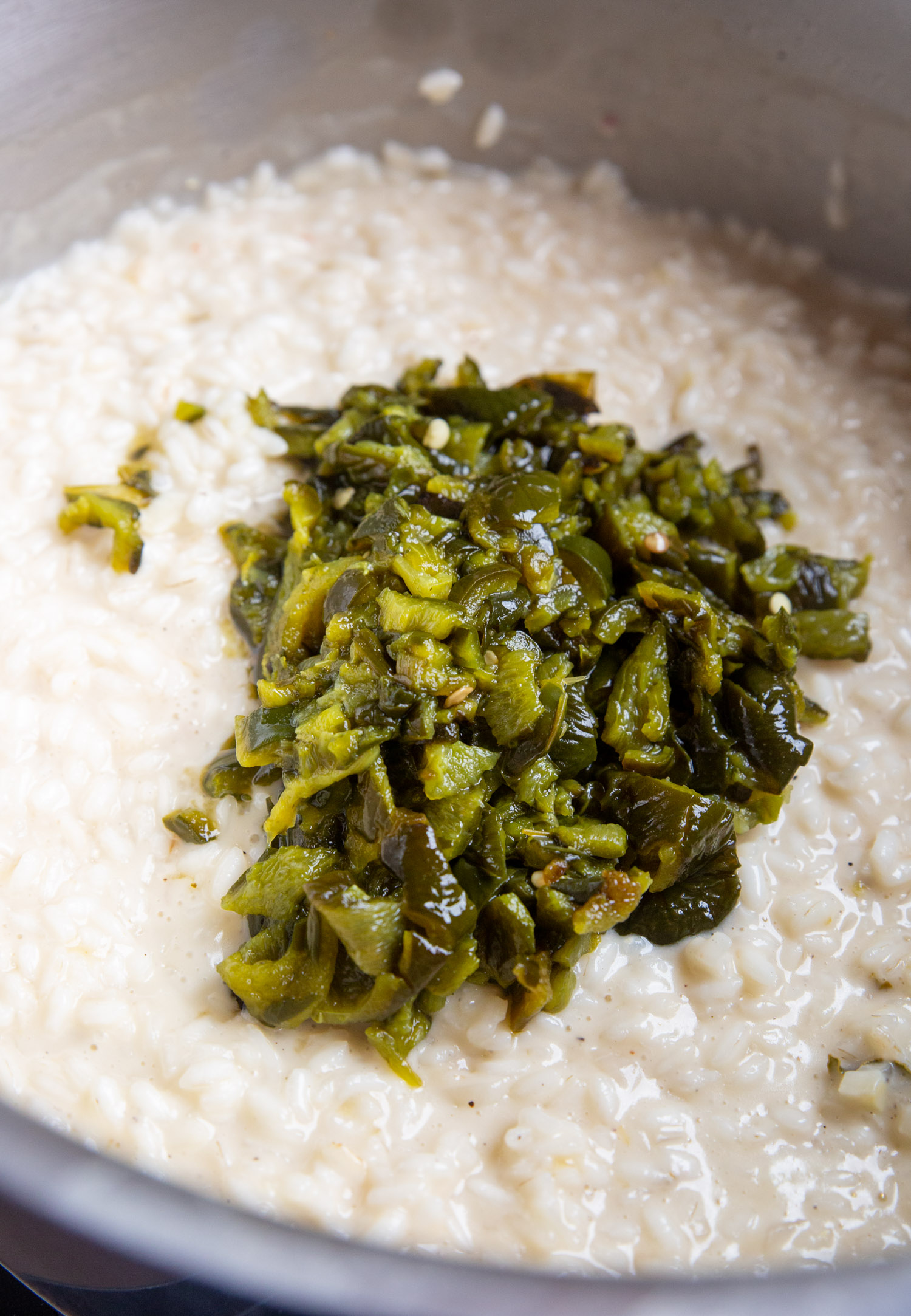 green chiles atop the completed risotto in a stock pan