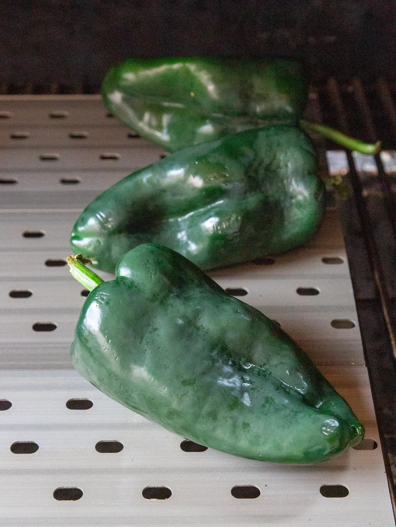 Fresh poblano chiles on the grill, prepped for roasting.