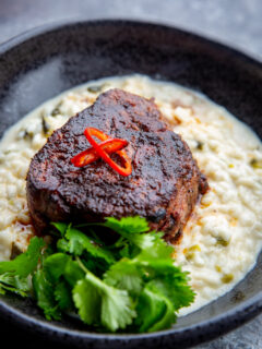 A big bowl of mole butter steaks sitting on top of green chile risotto