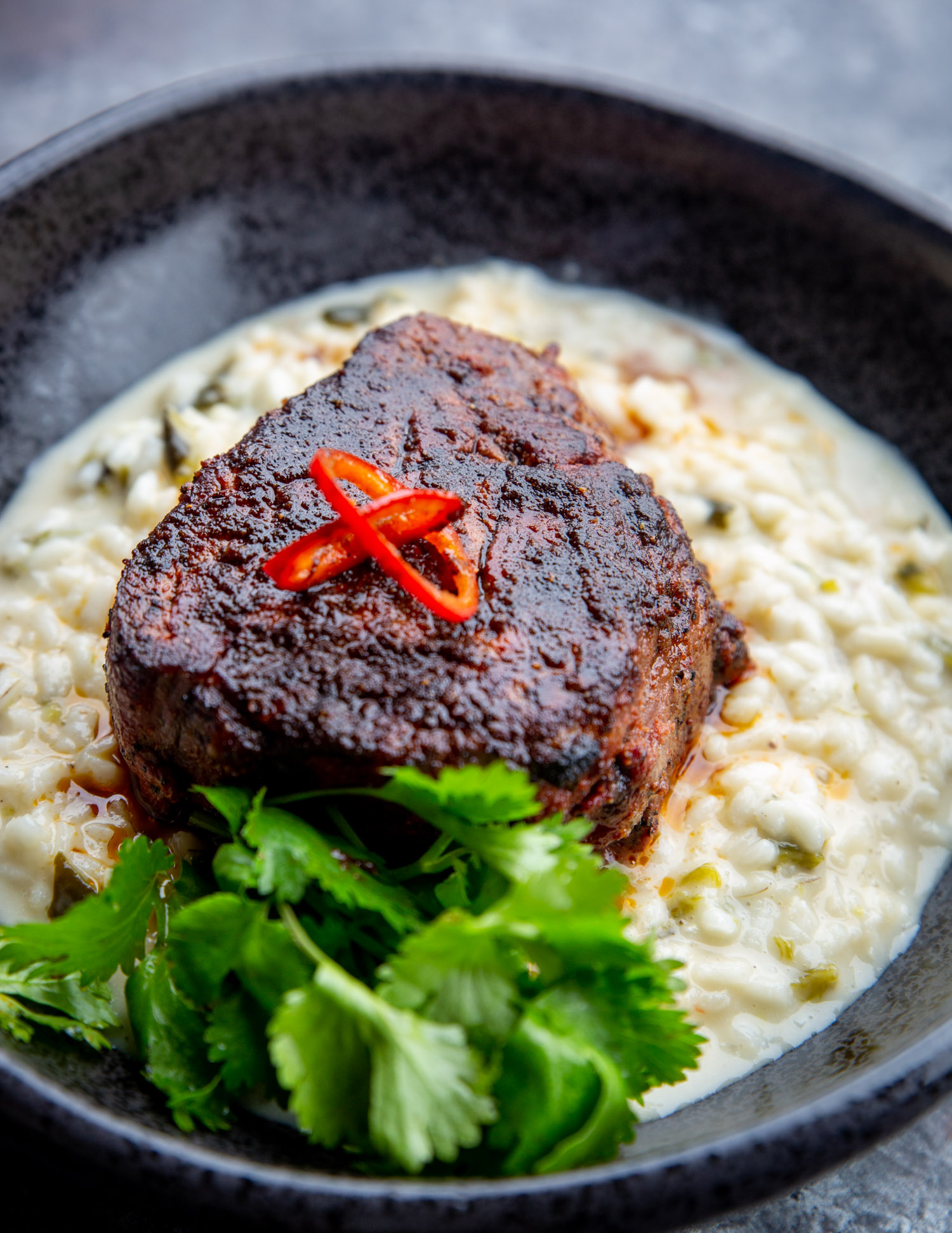 A big bowl of mole butter steaks sitting on top of green chile risotto