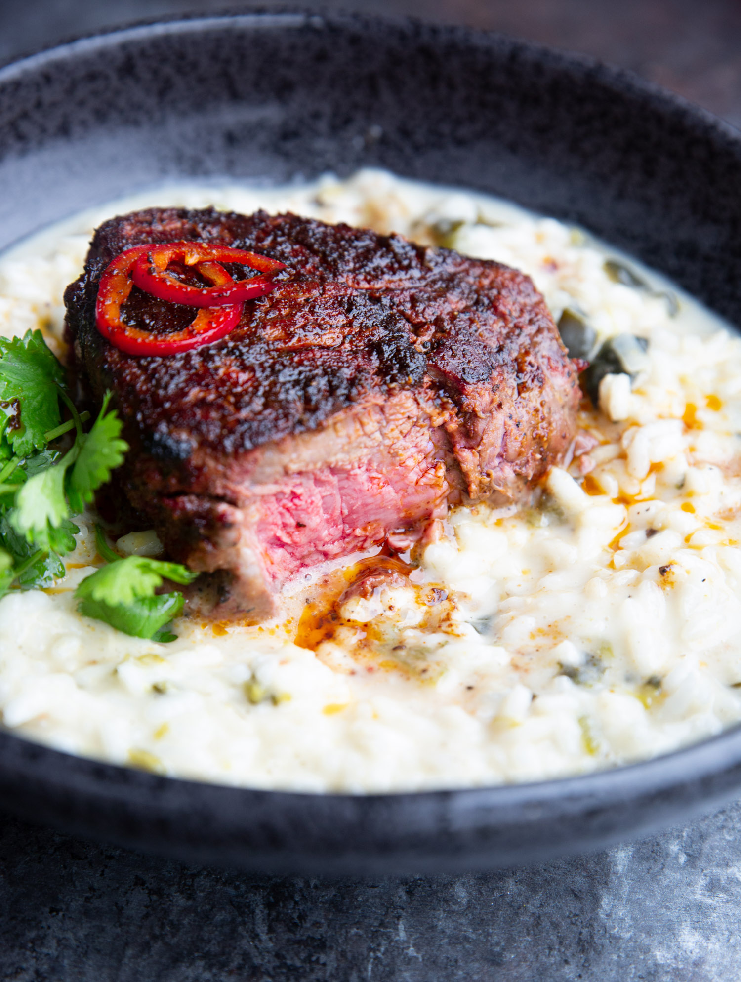 A Grilled Steak with Mole Butter on a black plate