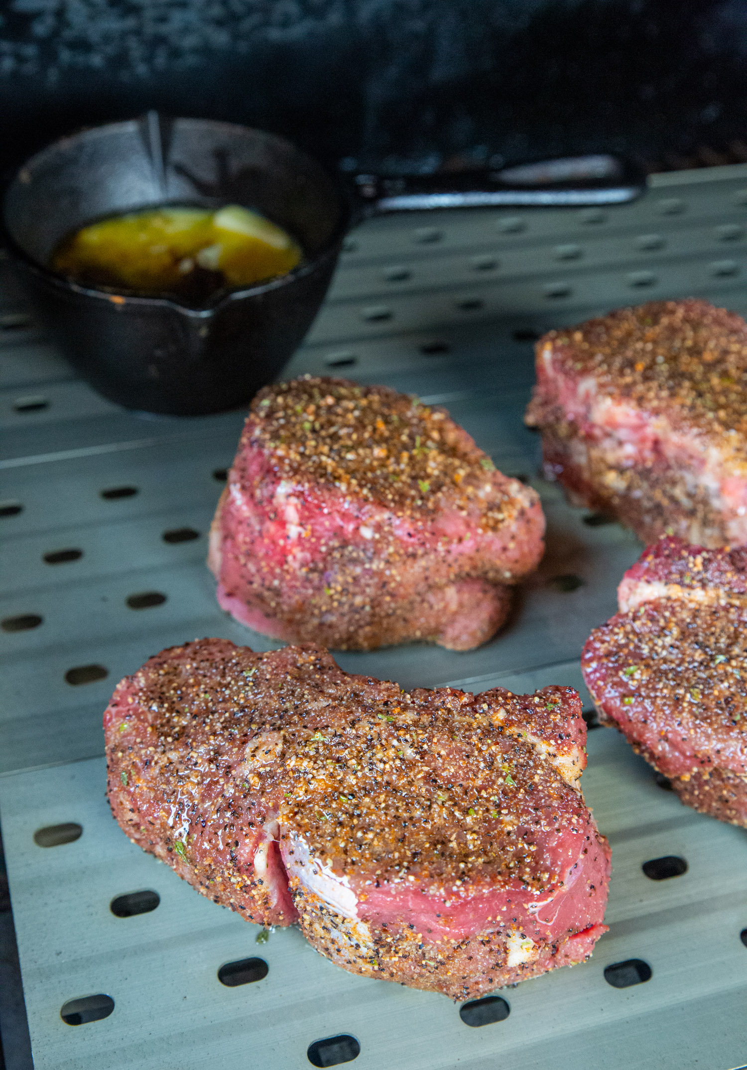 steaks sitting on the grill with the pan of mole butter near by