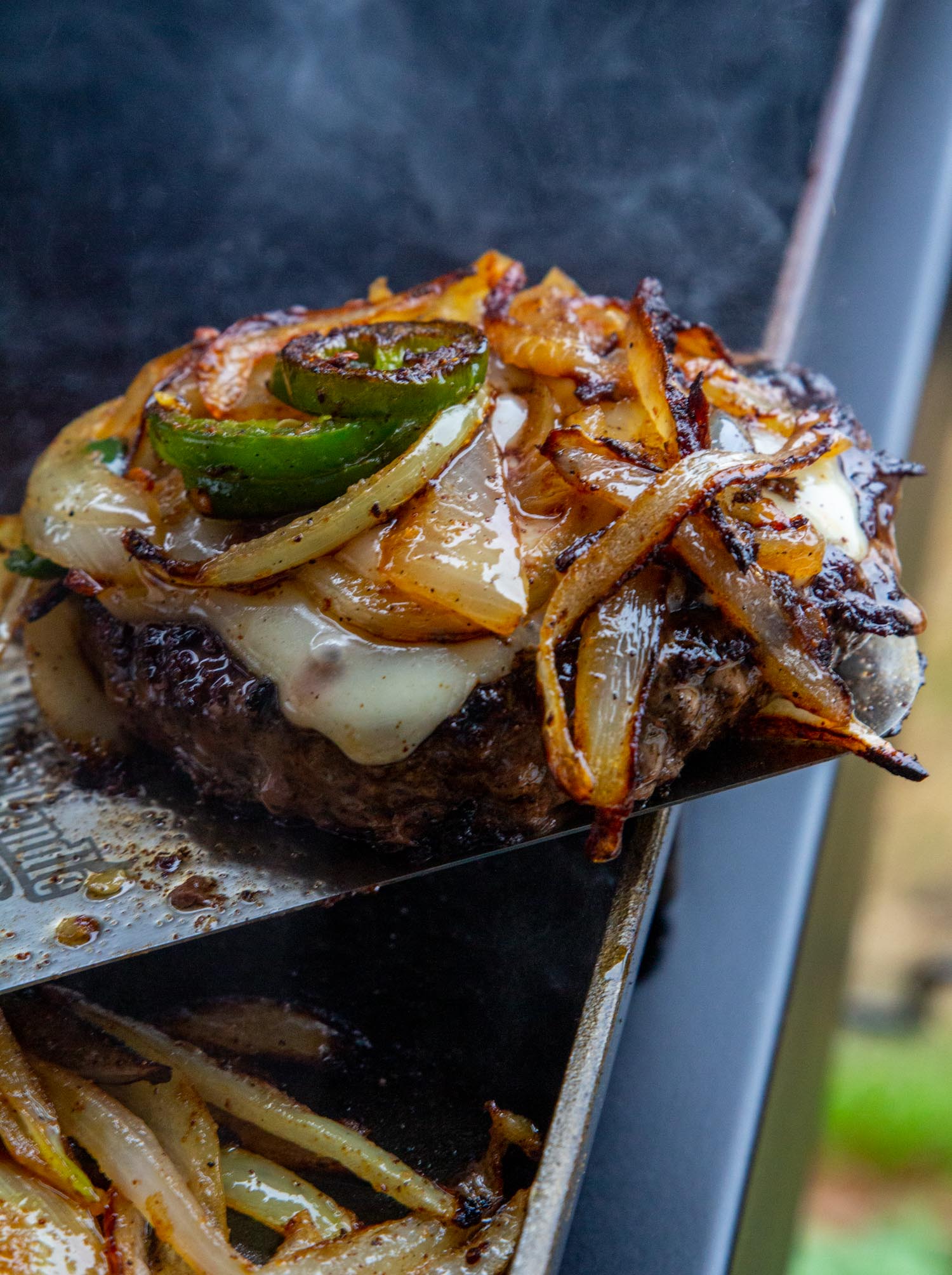 A completed smash burger perched on a large griddle spatula on top of the Blackstone griddle