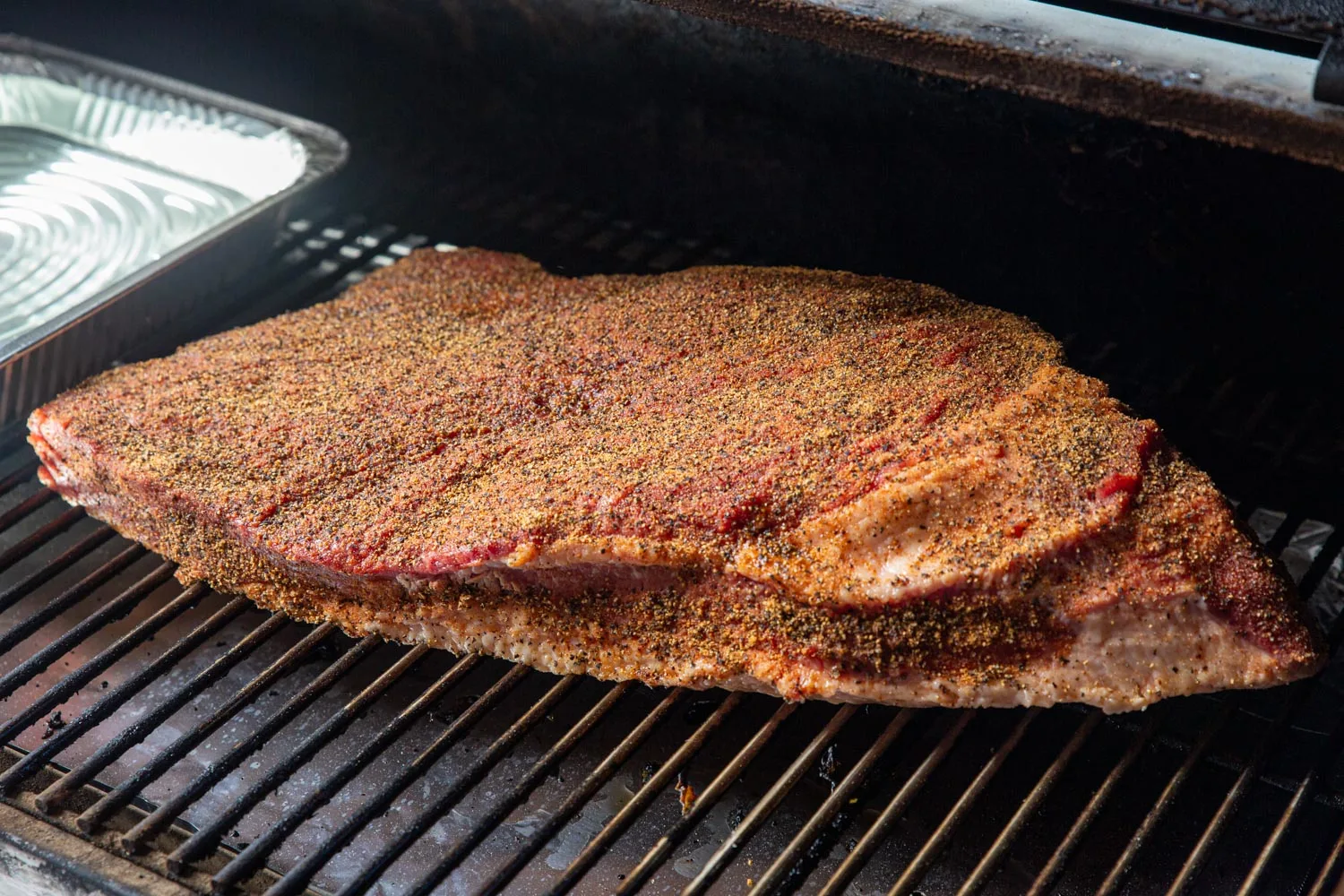 Brisket on the pellet grill, ready to be smoked. The rub is generous but can breathe.