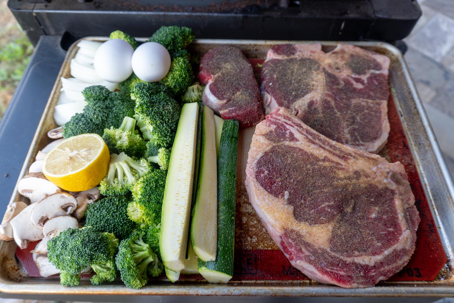 A cookie sheet loaded with hibachi favorites before cooking... vegetables, and hibachi steak.