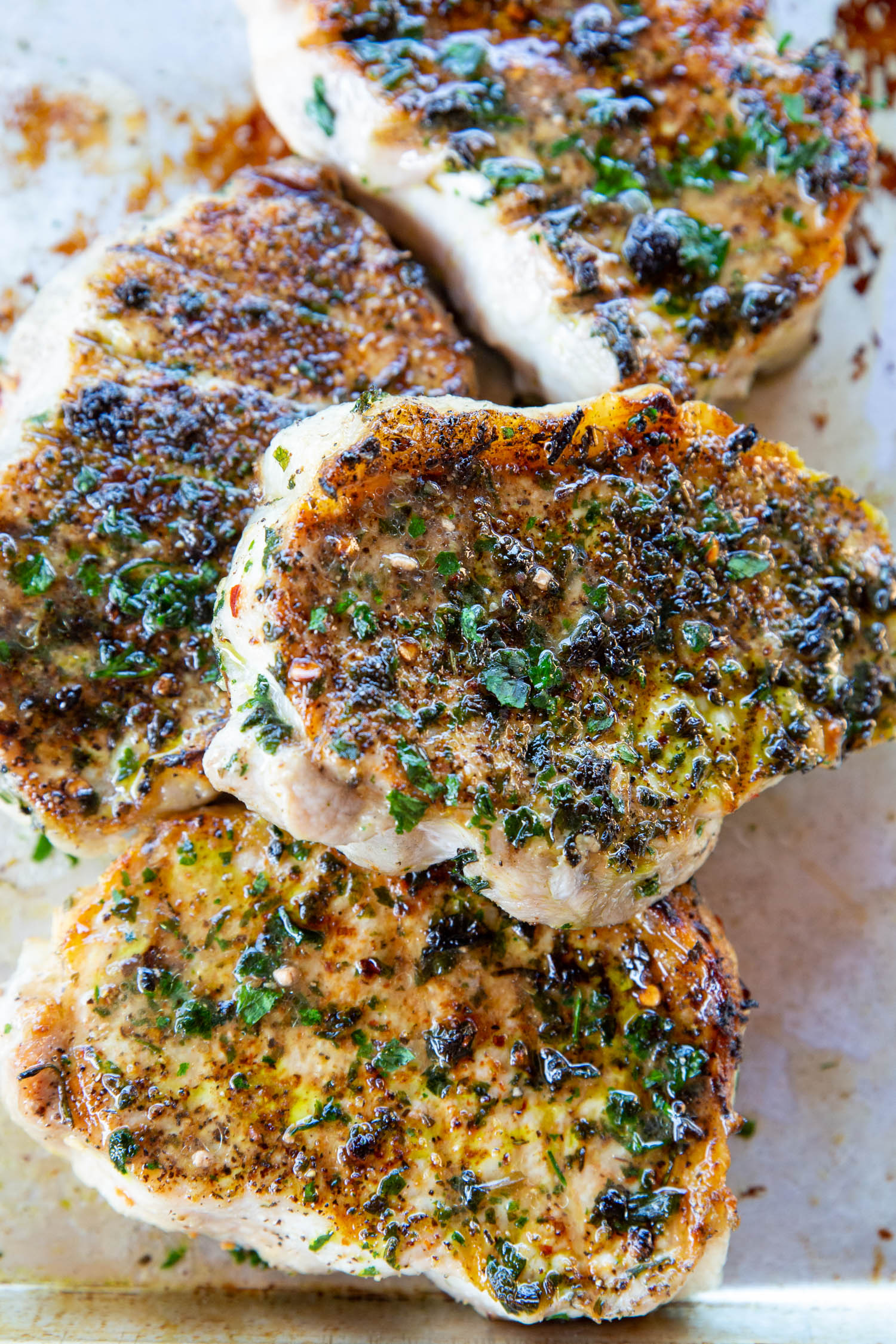 A plate of glistening grilled pork chops in herb marinade.