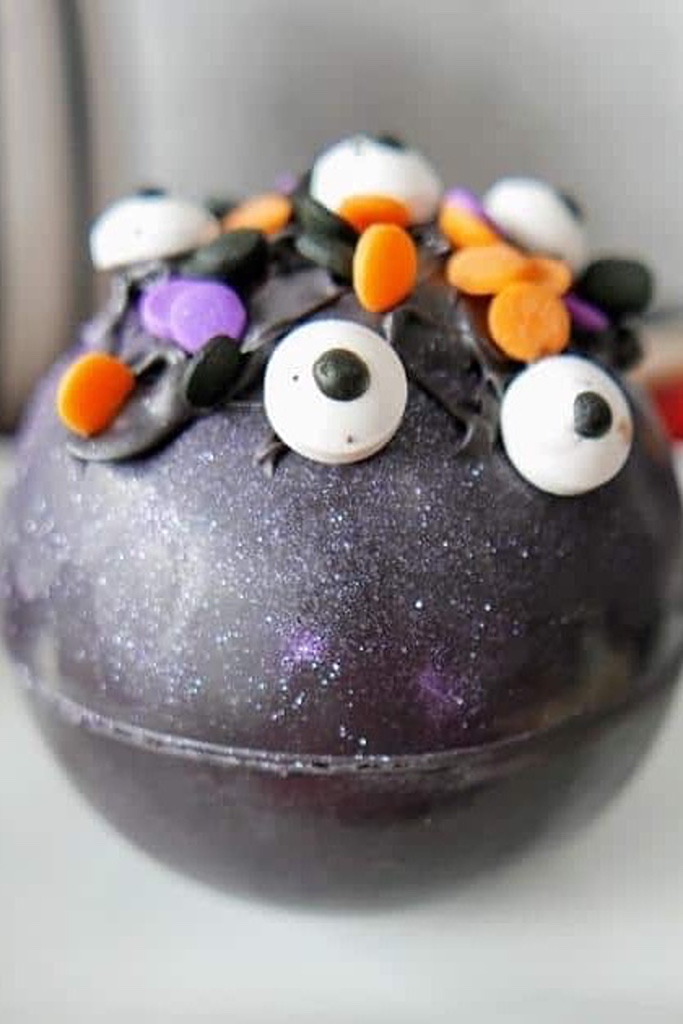 haloween hot cocoa bombs recipe- a black ball with googly eyes
