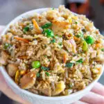 a bowl of chicken fried rice in a child's hand