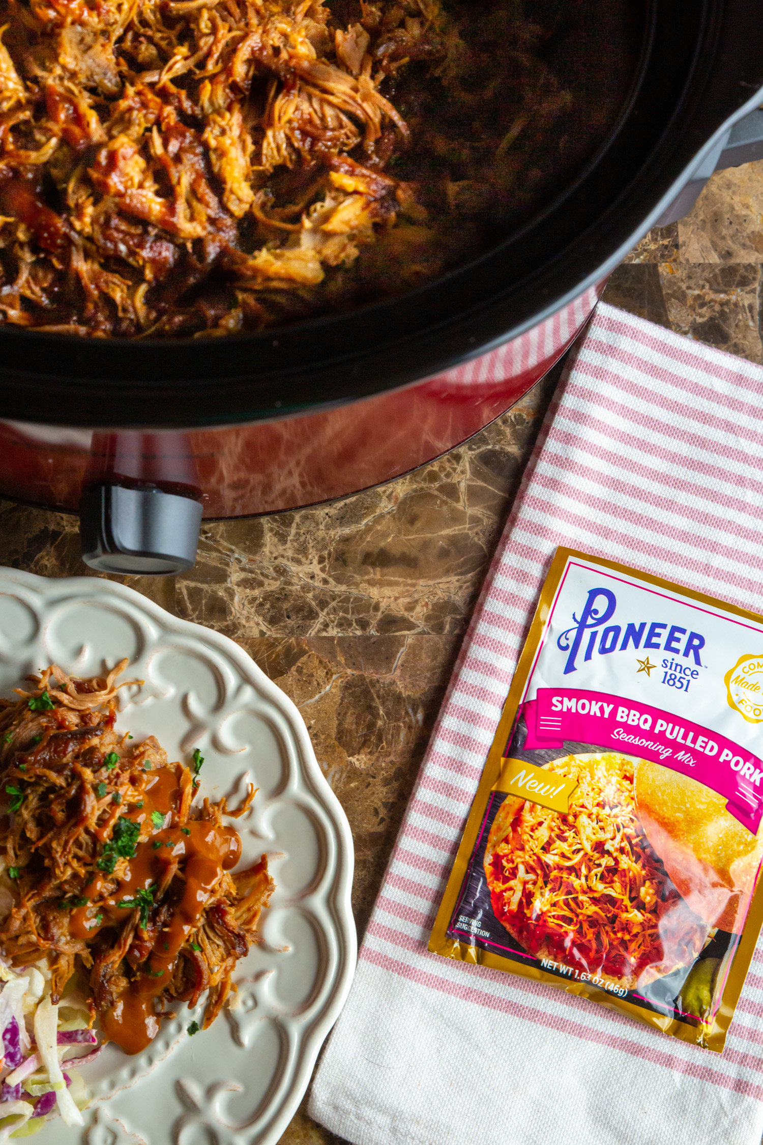 a plate of pulled pork next to a crock pot