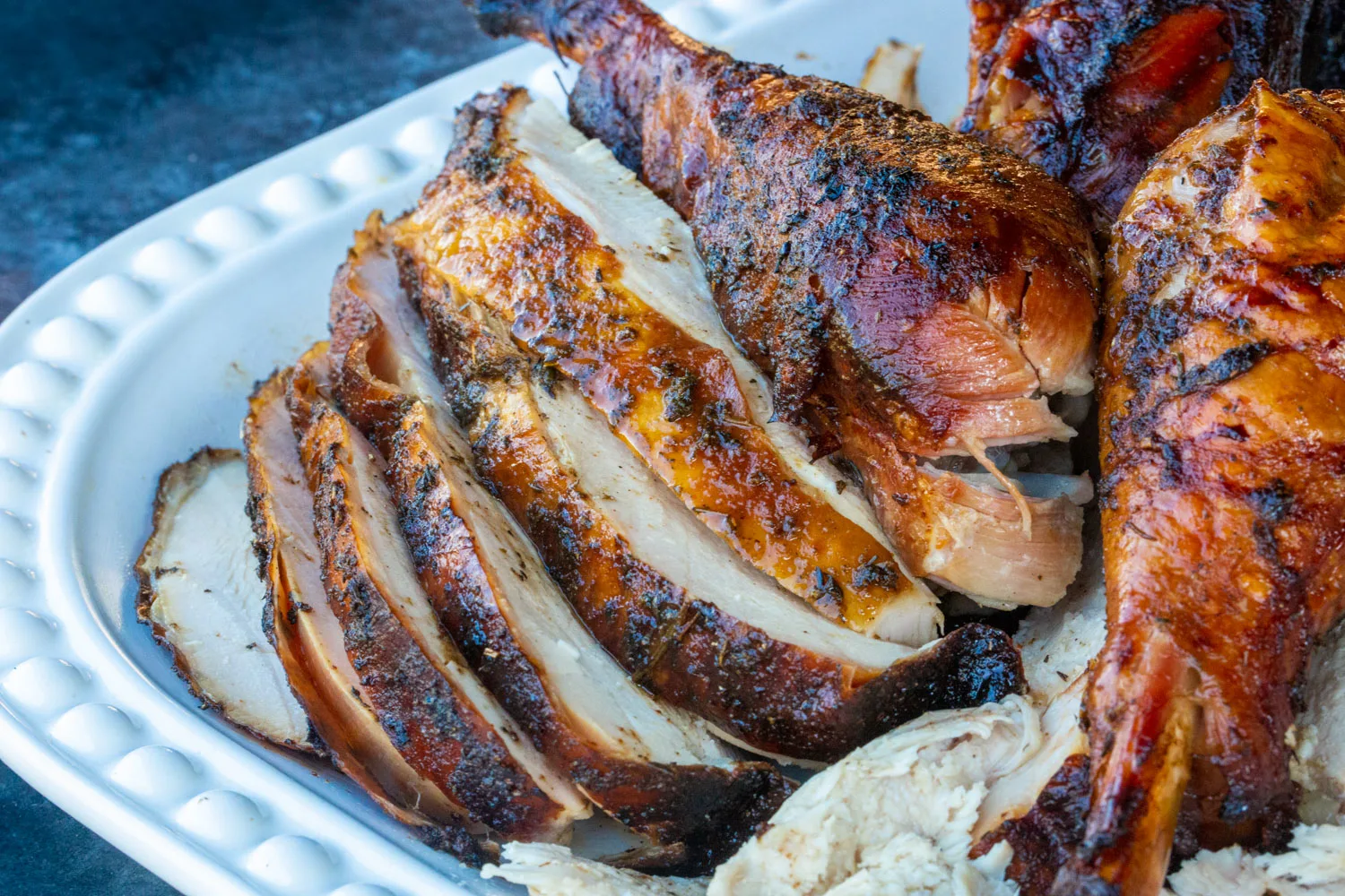 A white platter of golden brown sliced turkey meat