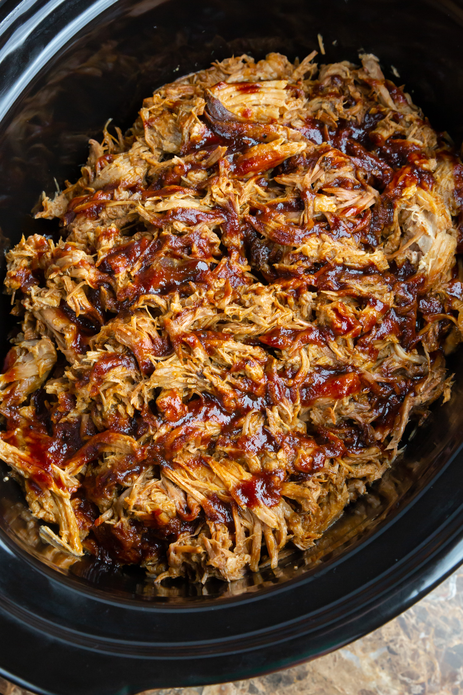 a crockpot recipe for pulled pork in a black crock pot