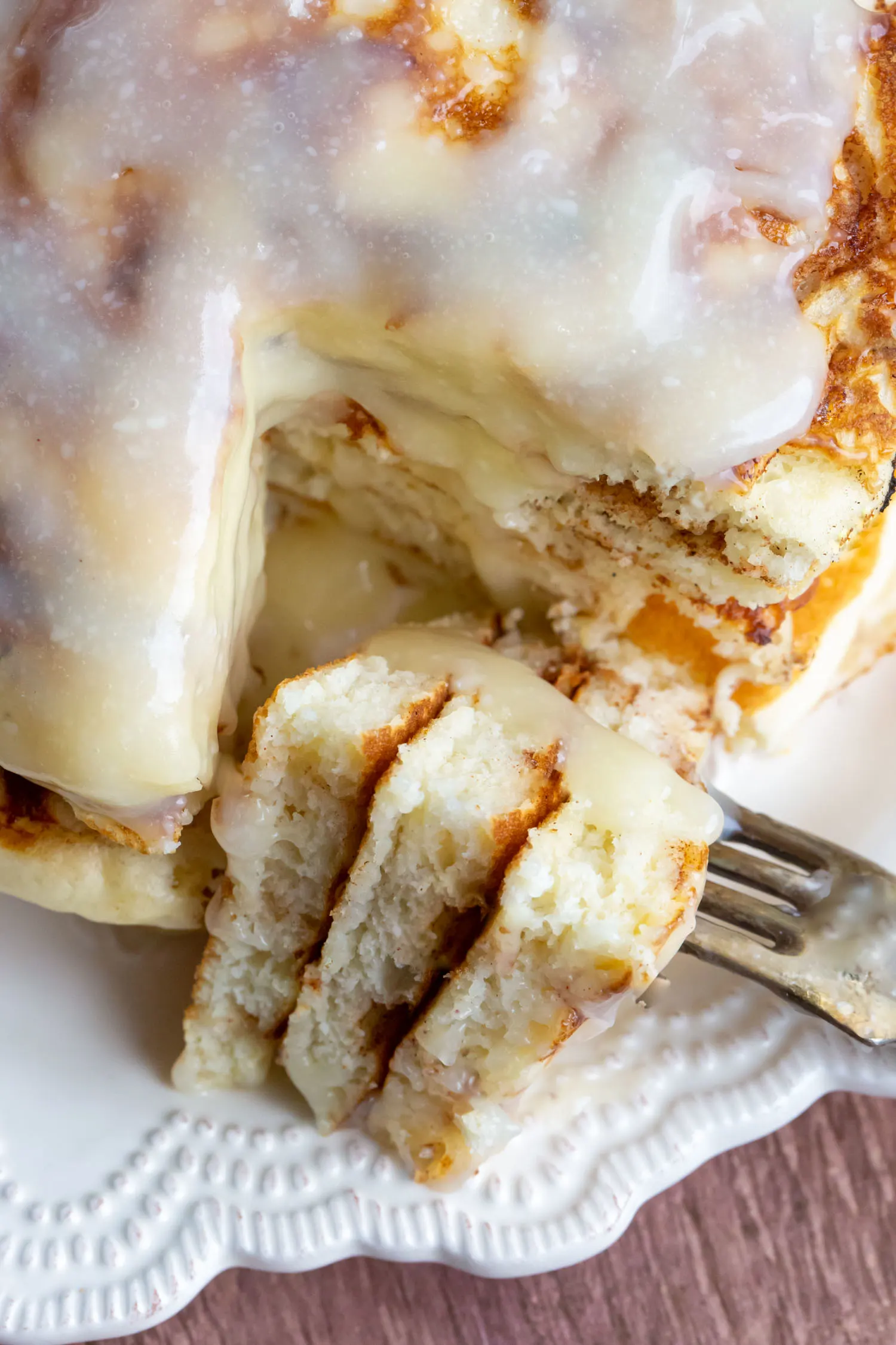 A slice of a stack of cinnamon roll pancakes on a fork