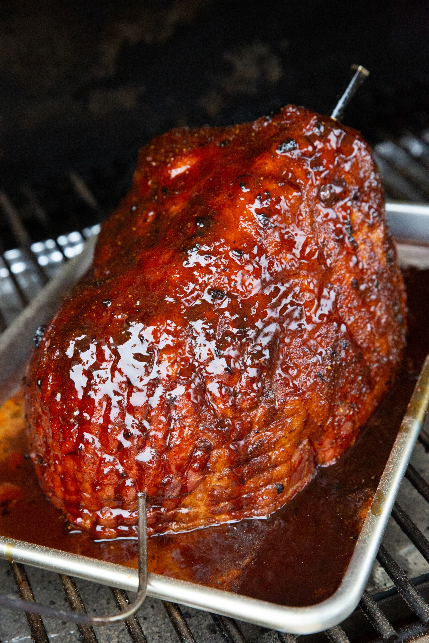 A red glazed and smoked ham on a barbecue.