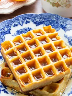 A golden brown waffle covered in syrup on a blue plate.